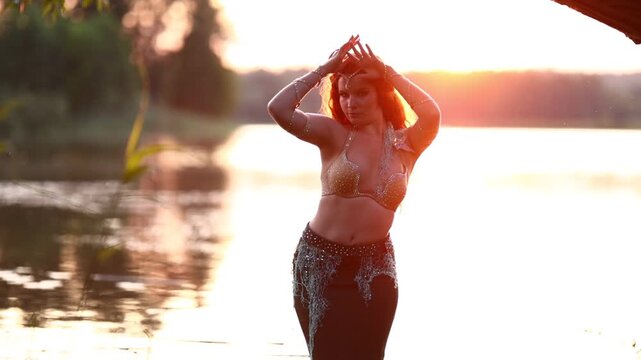 Girls in mermaid costumes dancing on the shore near the water at sunset