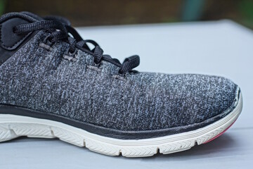 one gray black sneaker made of fabric and leather with white sole stands on a wooden table on a...