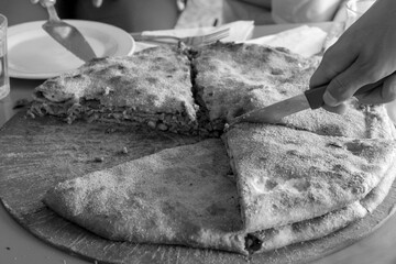 Medfouna, Berber pizza is a traditional and rustic homemade cooking originally from the  Morocco. Taken in Rissani Sahara desert, blurred background. Black and white
