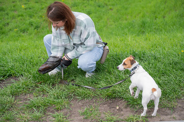 A woman cleans up dog excrement while on a walk.