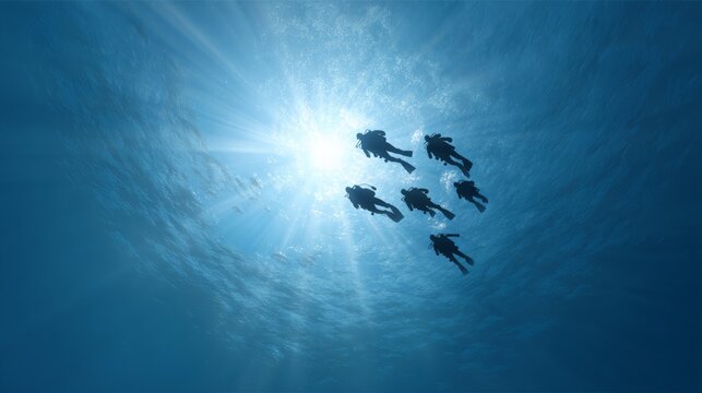 Sunbeams filtering through the surface illuminate a group of scuba divers as they explore the vibrant depths of the blue ocean, creating a captivating underwater spectacle - Powered by Adobe