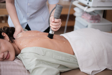Closeup shot, Hispanic female patient is recovery treated, gel ultrasound for back pain relief by...