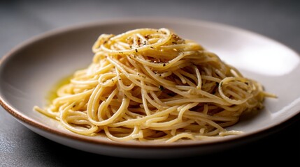 Plate of spaghetti on a black table. the spaghetti is cooked al dente and is covered in a creamy sauce. the sauce appears to be a light yellow color and is drizzled over the top of the spaghetti.
