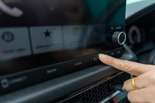 Finger of woman is pressing the answer button on a car phone. Bluetooth connection button in car, wireless pairing, hands-free feature.
