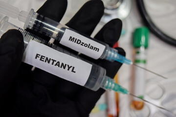 Midzolam and Fentanyl vaccination drug syringe in black gloved hands. Medical concept