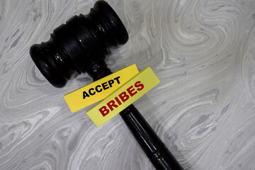 Concept of accept bribes write on sticky notes with gavel isolated on Wooden Table.