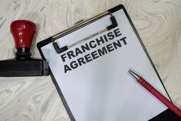 Concept of Franchise agreement write on clipboard isolated on Wooden Table.