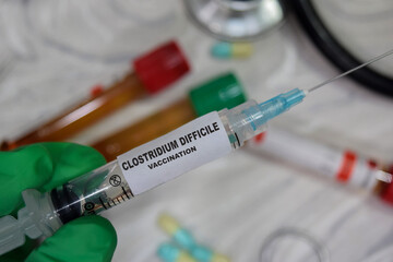 Clostridium difficile vaccination drug syringe in green gloved hands. Medical concept