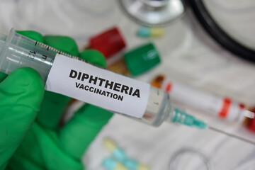 Diphtheria vaccination drug syringe in green gloved hands. Medical concept