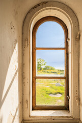Blick aus dem Fenster des Leuchtturms Hammerfyr, draußen grüne Landschaft und blauer Himmel zu sehen, vertikal