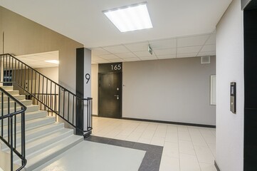 Modern building interior with stairs, elevator, door marked 