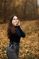girl in jeans and a black sweater in the forest in autumn