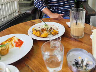 Serve various snacks and drinks on a warm wooden table, in an outdoor cafe. with natural blur.