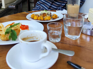 Serve various snacks and drinks on a warm wooden table, in an outdoor cafe. with natural blur.