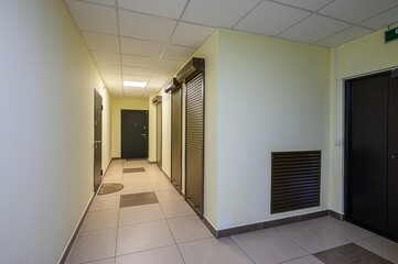 bright hallway with tiled floors, yellow walls, and dark doors. Shutters line one side