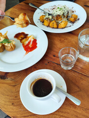 Serve various snacks and drinks on a warm wooden table, in an outdoor cafe. with natural blur.