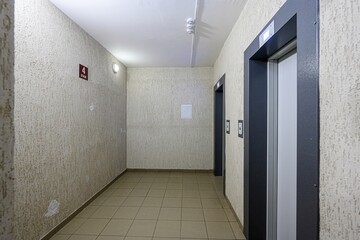 hallway with tiled floor, textured walls, elevators, and a sign indicating the floor number