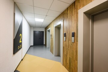corridor features elevators, wood-paneled walls, floor markers, and ceiling lights