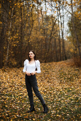 Girl in jeans and a white sweater in the forest in autumn