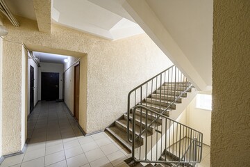 view of a building interior with stairs and a hallway. The walls are textured, and there are...
