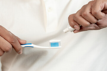 A close-up shot of a man squeezing toothpaste onto a toothbrush, part of a healthy morning dental...