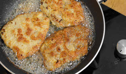 Pork chops frying in oil in a pan