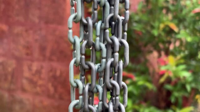 Closeup view of metal chain hanging and water droplet on spreading on it