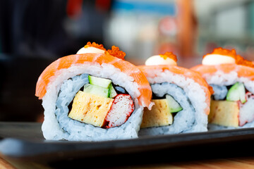 Fresh and colorful sushi roll with salmon, tamago, crab stick, cucumber, and rice, served on a white plate. Perfect for Japanese cuisine, food menu, or restaurant promotions