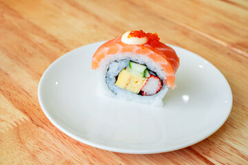 Fresh and colorful sushi roll with salmon, tamago, crab stick, cucumber, and rice, served on a white plate. Perfect for Japanese cuisine, food menu, or restaurant promotions