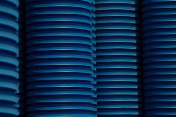 This is a detailed closeup view of a neatly arranged stack of cylindrical blue plastic pipes,...