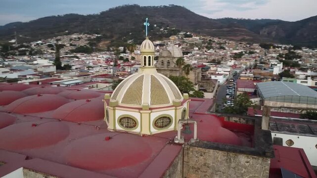 Drone flying around the rear dome of Ciudad Guzman Cathedral in the evening with a hilly backdrop