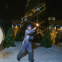 happy, joyful children on a walk by the Christmas tree with sparklers, a child celebrating the new...