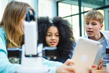 Smart students exploring robotics through digital devices in high-tech classroom, combining coding and creativity in hands-on STEM education.