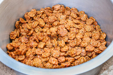 High-angle view of many golden brown fried fish balls arranged in a large stainless steel pot.