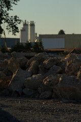 In the foreground, there is a varied and somewhat haphazard pile of rocks, with a structure clearly visible in the background