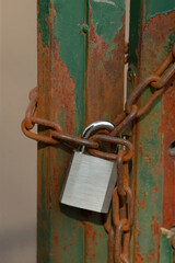 A sturdy padlock is firmly attached to a long, rusty chain, providing a sense of security but also showing signs of age and wear