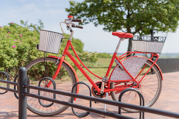 Ein hübsches rotes Damenfahrrad steht in einem Fahrradständer an der See, horizontal