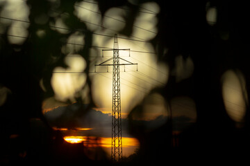 A tall telephone pole stands gracefully against a picturesque sunset in the background, captivating...
