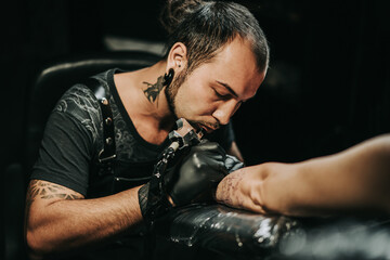 Obraz premium Man tattoo master with dreadlocks showing process creation tattoo, female body