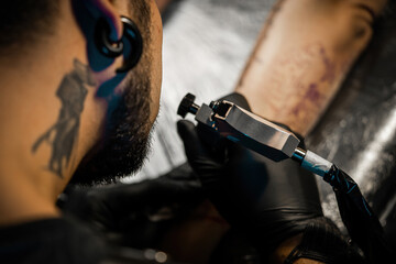 Tattooist doing tattoo for client with machine close-up.Getting tattoo in parlor