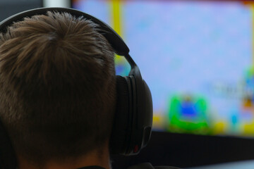 A man wearing large headphones is intensely playing a popular video game on his computer, fully...
