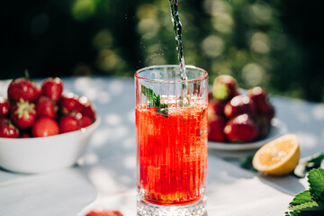 Mojito with lime and strawberry. Amazing iced strawberry lemonade drink on green