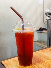 Tea mixed with honey and put in a plastic cup on the table.