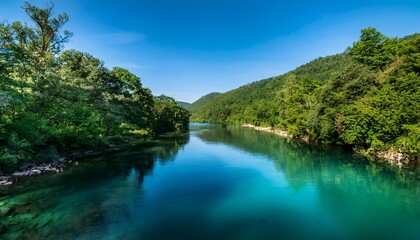 Obraz premium a river with a greenish blue color the water is calm and clear the trees surrounding the river are lush and green