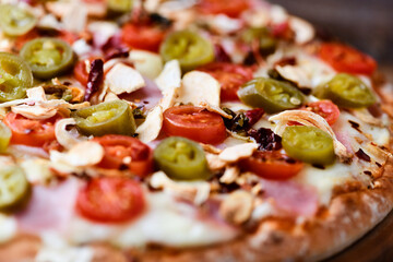 Pizza with ham, cherry tomatoes and mozzarella cheese. Wooden background. Soft focus. Close up.