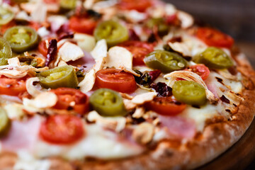 Pizza with ham, cherry tomatoes and mozzarella cheese. Wooden background. Soft focus. Close up.	
