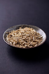 Dry Siberian ginseng (Eleutherococcus senticosus) on dark paper background. Close up.	