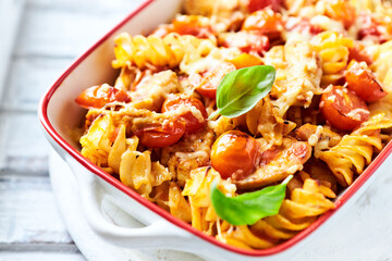 Pasta with chicken breast, cherry tomatoes and fresh basil. Bright wooden background. Close up.	