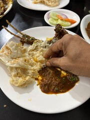 delicious Mutton curry and parotta served on different bowl and served on the table in a hotel