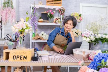 Asian senior woman, florist, small business, owner holding bouquet and smartphone in flower shop, presenting service, digital marketing confidence, and floral, modern aging people with technology